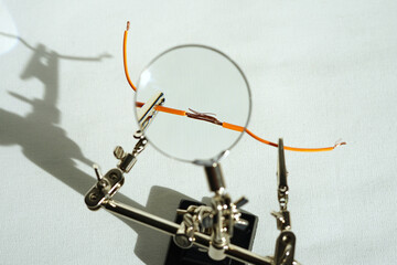 Two power wires are going to be soldered while being held in right position with alligator clips, and are good visible with the magnifying glass