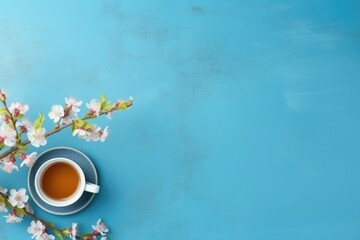 Obraz na płótnie Canvas Traditional Chinese tea with blooming tree branch on blue background, top view, copy space