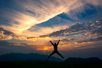 man jumping on mountain top over sky and sun light background