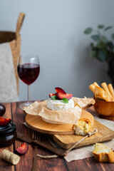 Camembert with plum and red wine on a wooden background