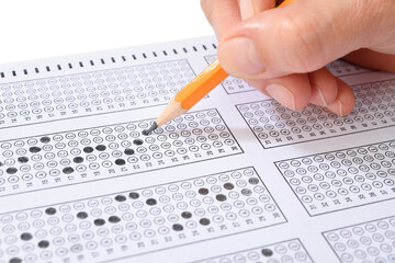 Student filling out answers to a test with orange pencil close-up   
