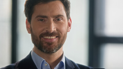 Close-up caucasian bearded man looking side and turning gaze to camera smiling successful mature...