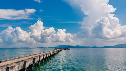 Obraz premium Pier bridge landscape at island with green mountain. Lush clouds against bright blue sky. MooK island, Thailand