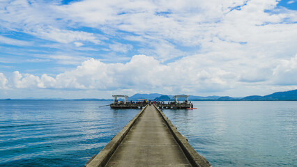 Pier bridge landscape at island with green mountain. Lush clouds against bright blue sky. MooK island, Thailand