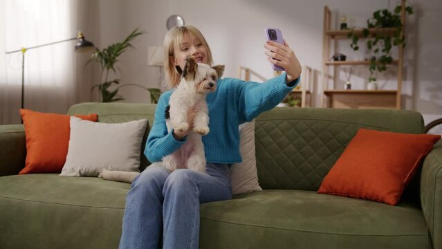 Female taking pictures with cell phone while holding puppy