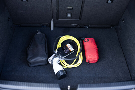 Electric car charger in car trunk. Electric car. Car trunk with charging cables. Modern car interior, car trunk. Portable in-cable charging box for electric car charging lying in a car trunk.