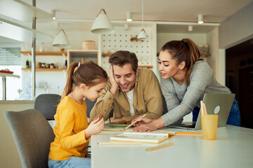 Family of three, enjoy time together, drawing in a coloring book with crayons at home, smiling.