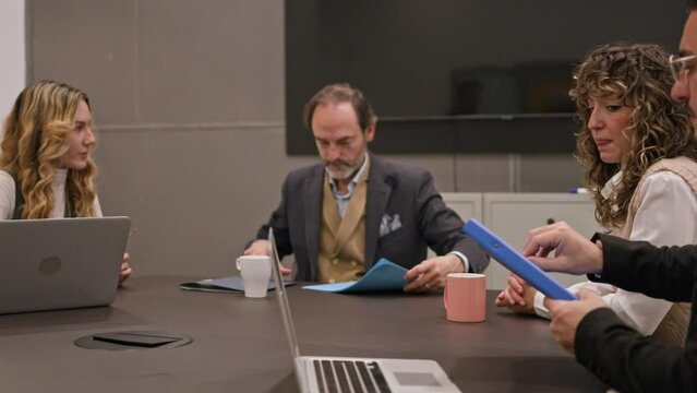 Professionals intently examining files and a laptop during a collaborative meeting in an office. 
