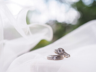 Obraz premium Diamond engagement wedding rings on bridal veil. Wedding accessories. Valentine's day and Wedding day concept.