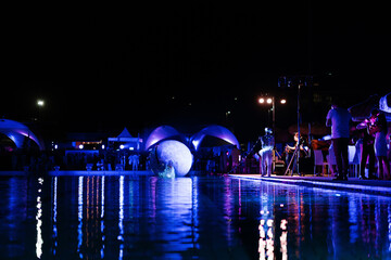 live show at the pool party while people dancing by the pool