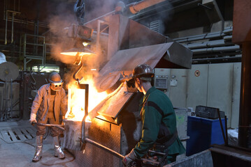 workers in a foundry casting a metal workpiece - safety at work and teamwork