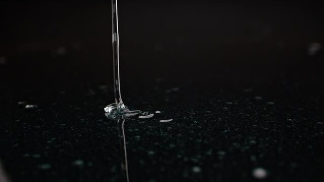 Gleaming slightly blue gel lands on a dark background, hinting at luxury skincare or bath products.