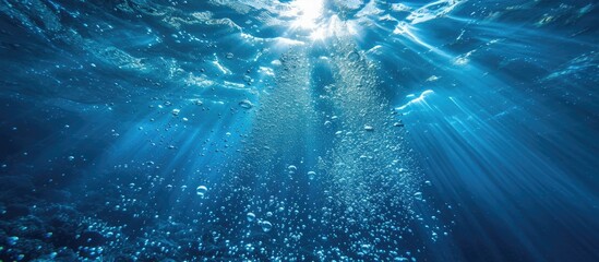 Underwater bubbles allow sunlight to penetrate the azure ocean depths dark blue. 
