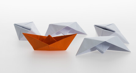 Orange paper boat and a lot of sinking ships
