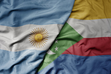 big waving national colorful flag of comoros and national flag of argentina .