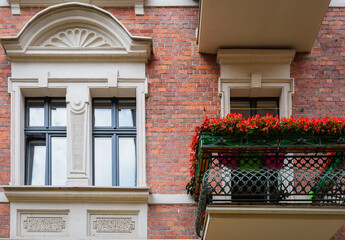 Windows decorated with flowers. Typical facades of buildings in Torun. Flowers under shuttered. A...