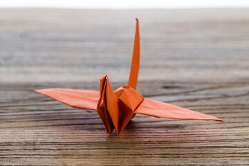 Orange origami paper crane on wooden table