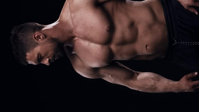Fit and sporty bodybuilder over black background. Bodybuilder training using barbell. The concept of sport and fitness.