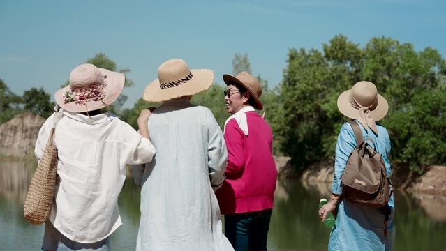Portrait, backside scenes are four elderly women are best friends, go out play go hiking, come out see beautiful nature after retirement, Standing and talking, resting tired, wear warm hat.