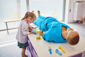 Adorable preschooler girl playing doctor