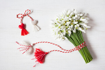 Bouquet of snowdrops flowers, red and white rope with tassels martenitsa, hearts on a wooden background. Postcard for the holiday of March 1 - 724825243