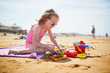 Adorable preschooler girl playing on the sand beach at Atlantic coast of Brittany, France