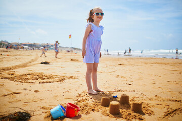 Adorable preschooler girl playing on the sand beach at Atlantic coast of Brittany, France