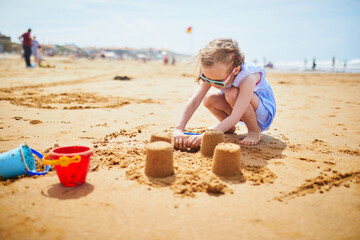 Adorable preschooler girl playing on the sand beach at Atlantic coast of Brittany, France