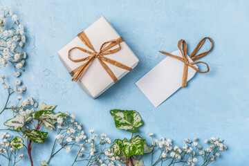 White gift box and label on a blue background with sprigs of gypsophila. Happy Easter greeting card, Happy Birthday, Mother's Day, Happy Father's Day, Happy Wedding Day.