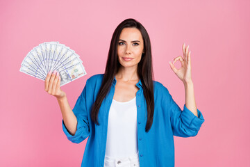 Portrait of confident positive woman wear stylish shirt hold dollars in arm showing ikey approve...