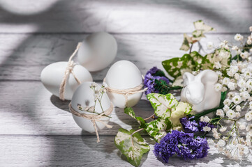 Obraz na płótnie Canvas Easter eggs decorated with gypsophila sprigs, white Easter bunny on a white wooden background.Easter background.
