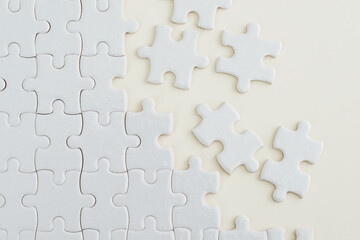 Unfinished white puzzle pieces on white background