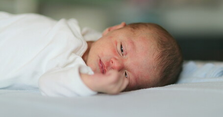 newborn baby infant face waking up and opening eyes