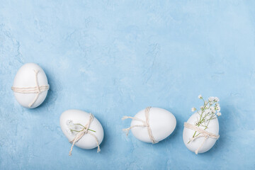 White Easter eggs decorated with twine and sprigs of gypsophila on a blue background. Easter...