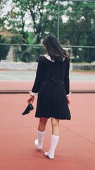 woman walking on the street holding a shoes