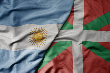 big waving national colorful flag of basque country and national flag of argentina .