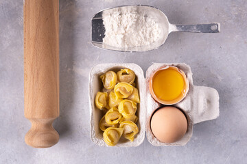 in the foreground, seen from above, raw tortellini Bolognese style, fresh eggs and flour.