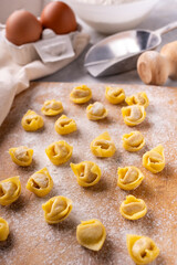on the floured cutting board, raw tortellini Bolognese style, fresh eggs and flour.