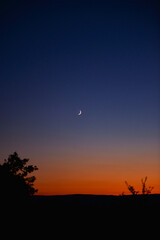Young crescent moon on a clear sky at the end of the day in the summer