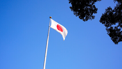 Japanese flag waving in wind with blue sky. Japan banner blowing, soft silk