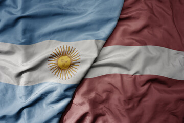big waving national colorful flag of latvia and national flag of argentina .