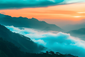 Mountainous landscape at sunset, fog enveloping layers of mountains with vibrant orange and pink sky. Vegetation visible, serene and splendid
