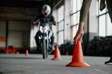 Motorbike driving school lesson with instructor putting cone on track