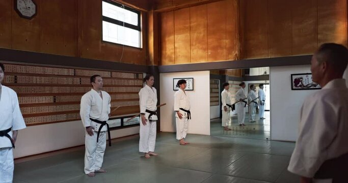 Black belt students, bow or sensei in dojo to start aikido practice, discipline or self defense. Combat demonstration, Japanese people learning respect or ready for fighting class or fitness training