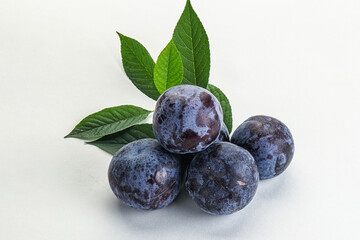 Raw purple plums heap with leaves