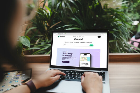 Bangkok. Thailand. FEB 1,2024 : Woman hands using tripadvisor website on a laptop macbook pro for booking the apartments and searching interesting place. Close up. Indoor shoot...