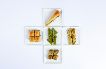 Top view of baklava varieties on white plates isolated on white background.