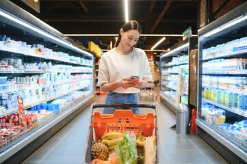 Female customer uses mobile phone in supermarket