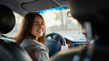 Joyful young woman sitting in a car, looking at the camera, expressing joy and excitement for obtaining her drivers license. Lifestyle and success concept - 724850057