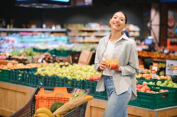 young adult woman choosing apples in grocery store. lifestyle